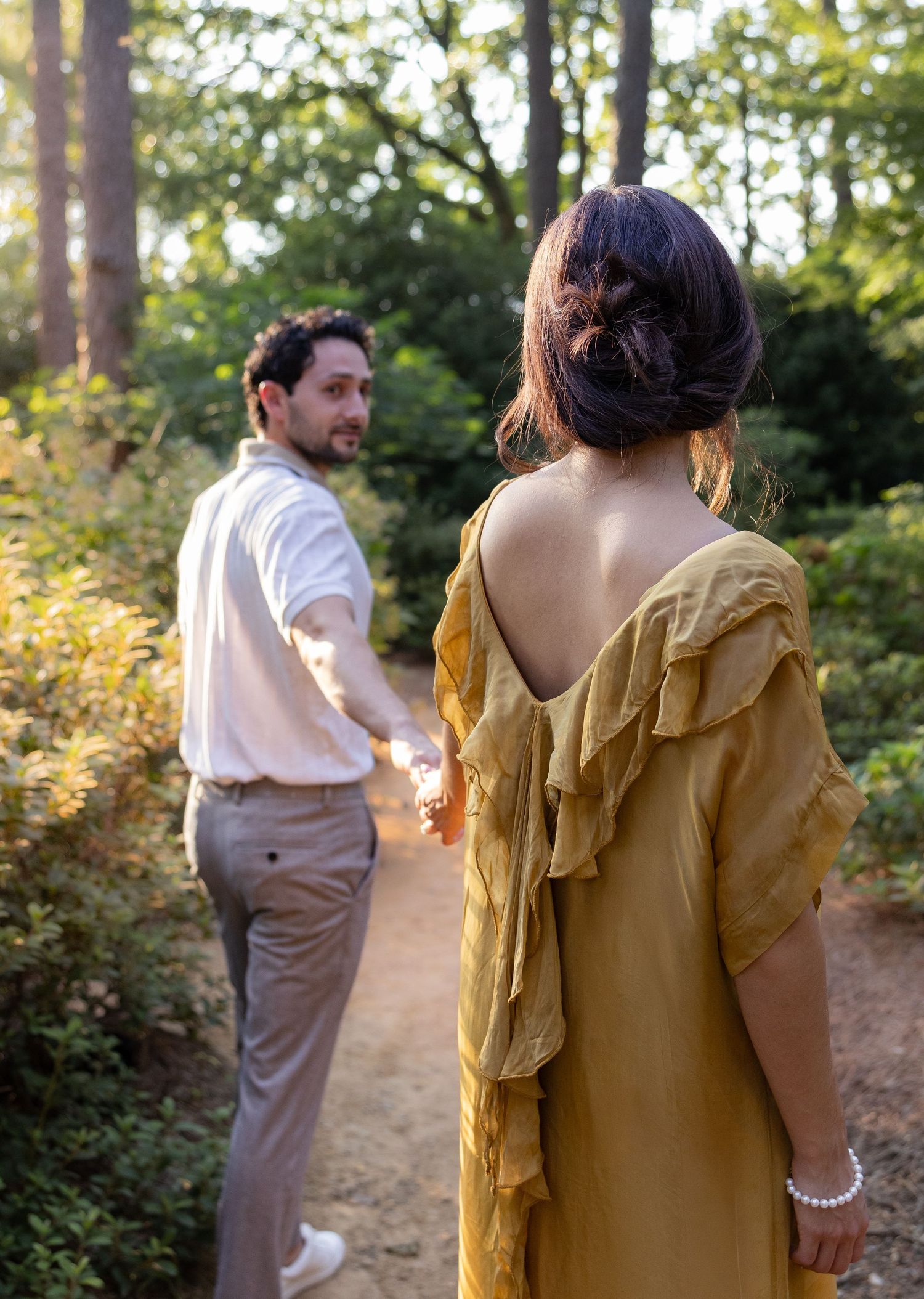 A couple walking away on a wooded path in warm afternoon light.