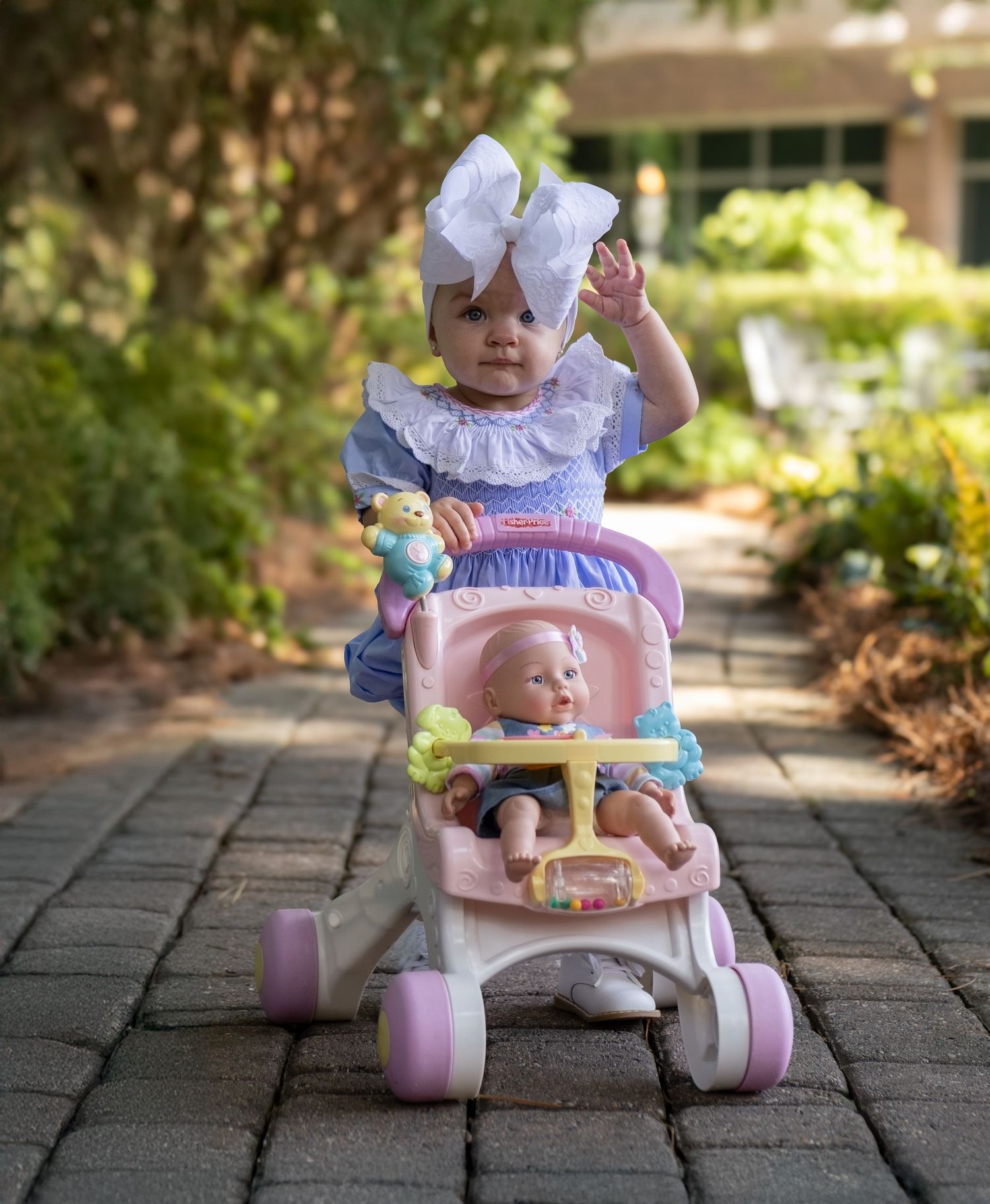 Baby toy car with pink wheels on a brick paver patio.
