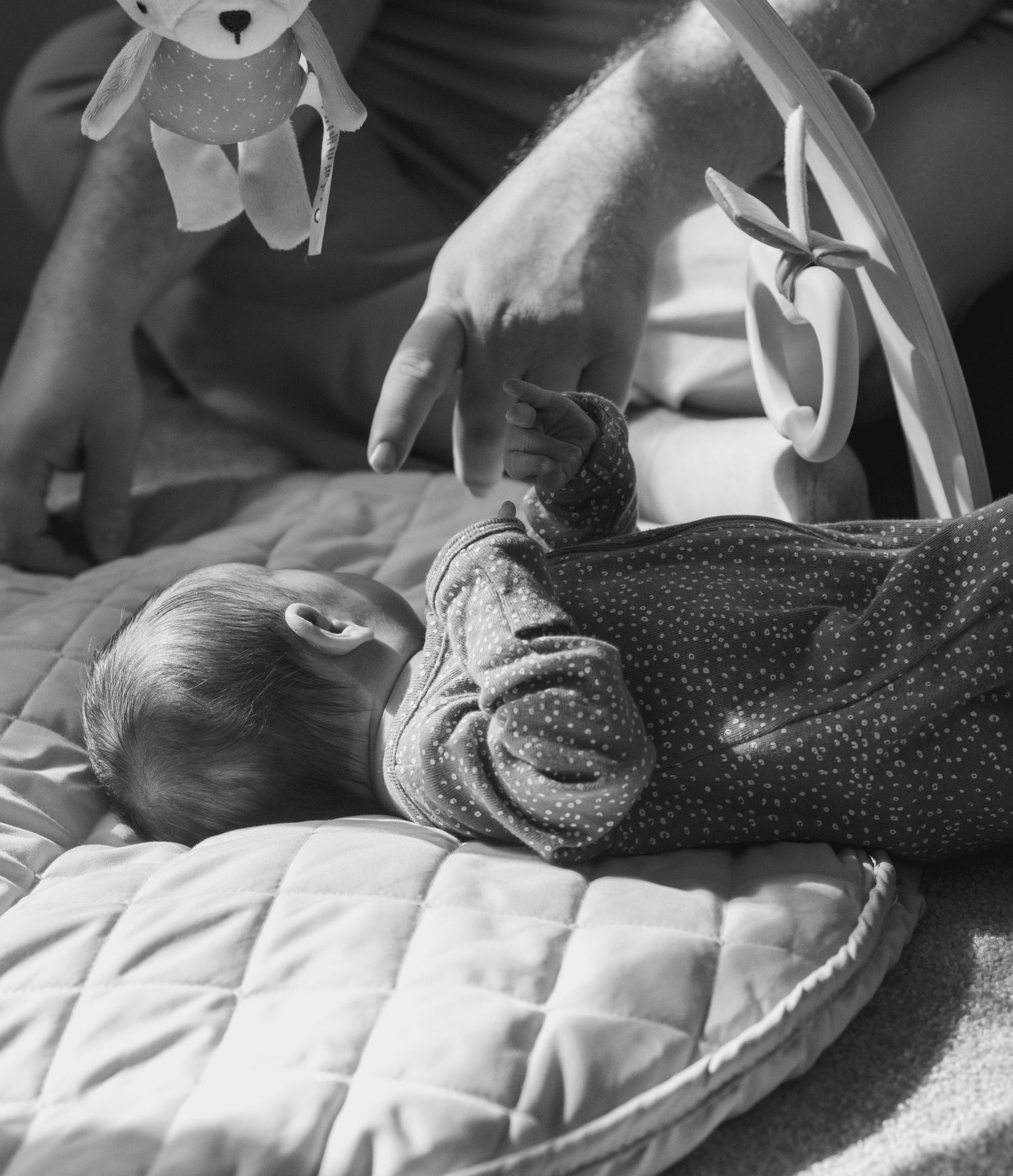 Black and white image of a baby lying on a polka dot blanket.