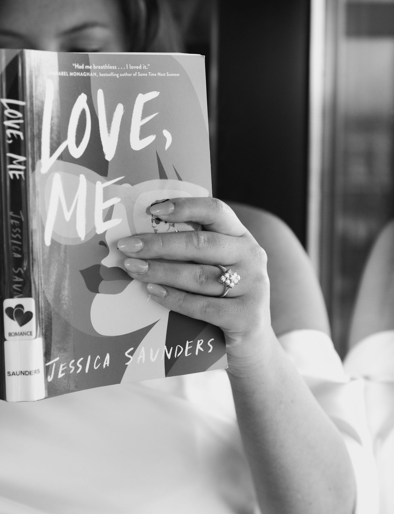 Black and white photo of hands holding a book titled 'Love, Me'.