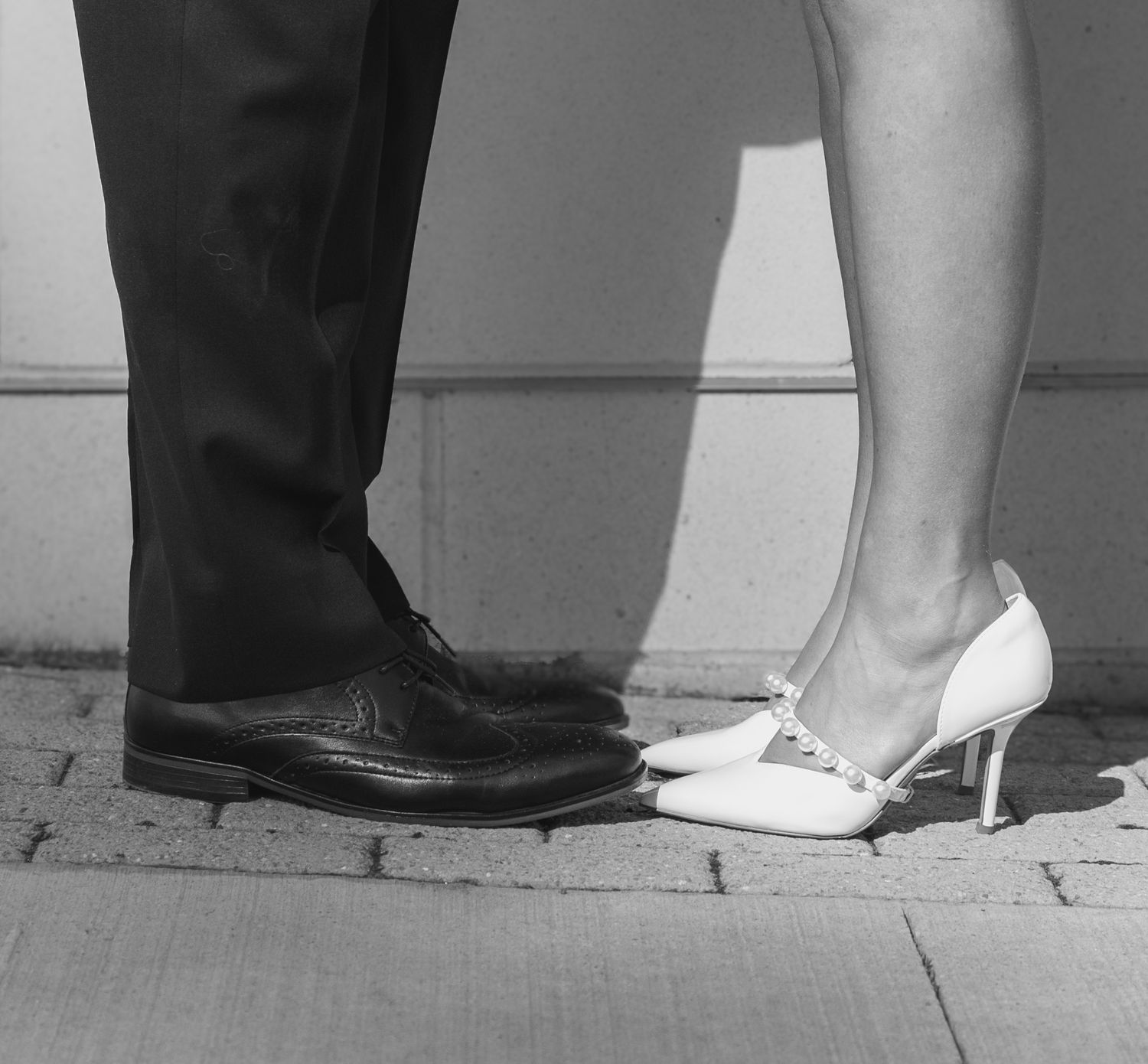Black and white photo of formal shoes on pavement.