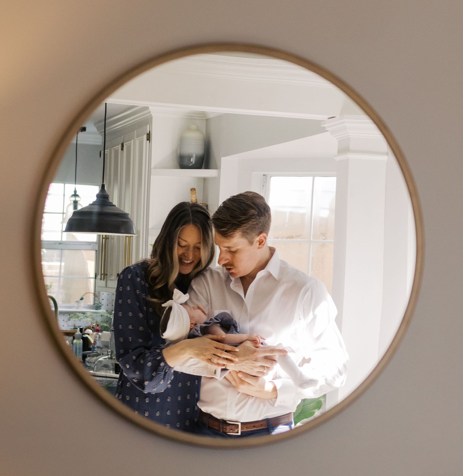 A couple shares a tender moment while holding their newborn baby in a mirror selfie.