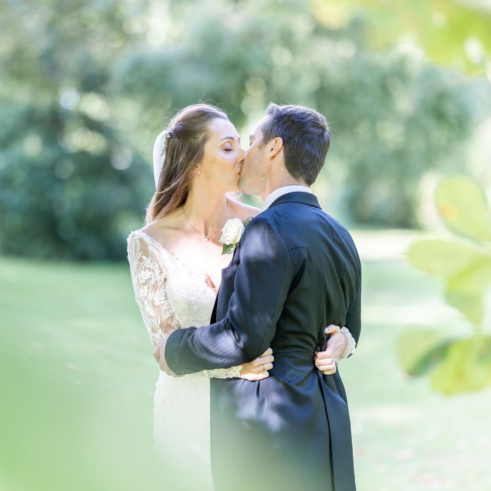 A romantic wedding couple sharing a tender kiss at their Horsted Place wedding in Sussex with soft bokeh background.