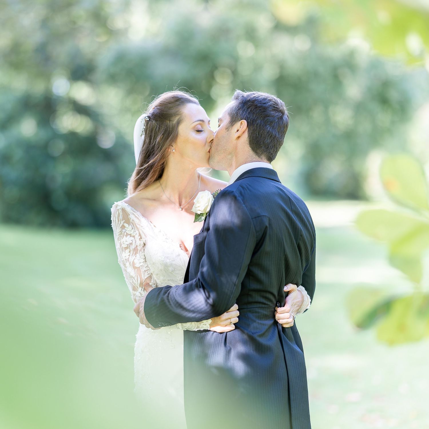 A romantic wedding couple sharing a tender kiss at their Horsted Place wedding in Sussex with soft bokeh background.