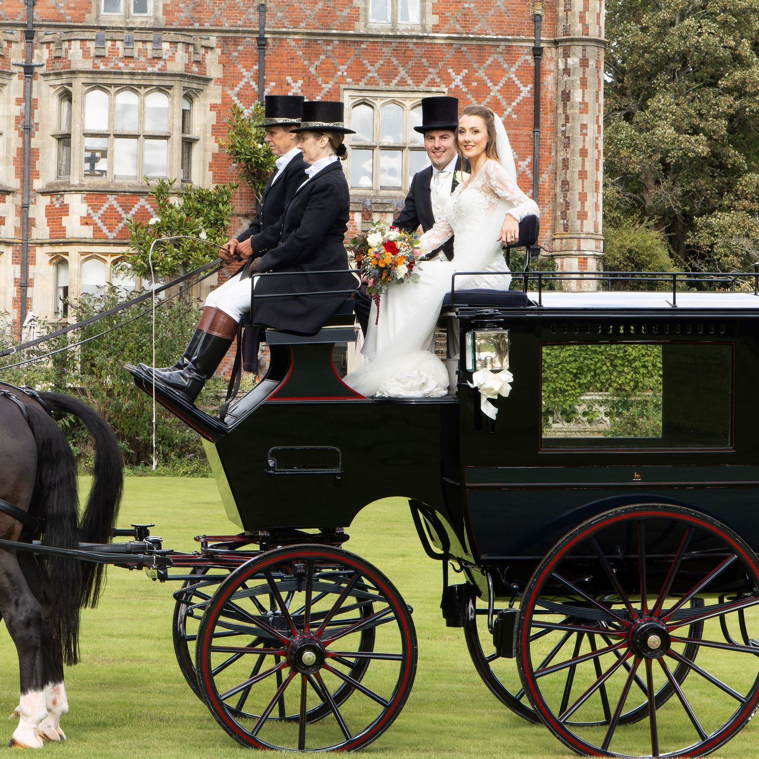 A classic black horse-drawn carriage sits on manicured green grounds of Horsted Place, East Sussex.