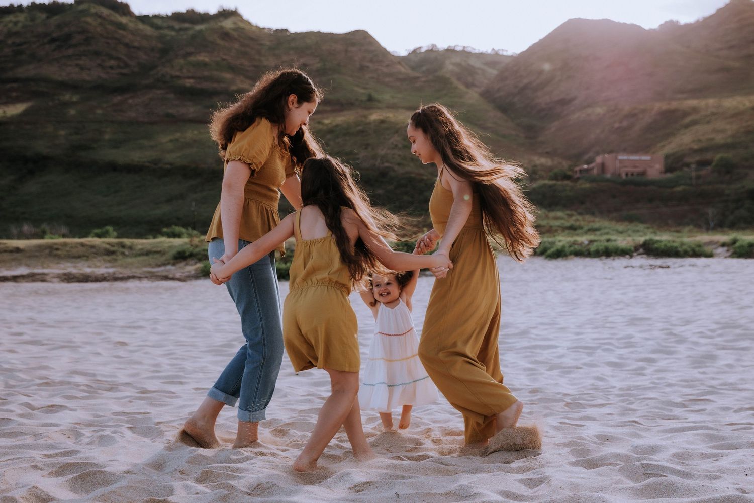 Group playing and splashing in shallow ocean water at sunset.