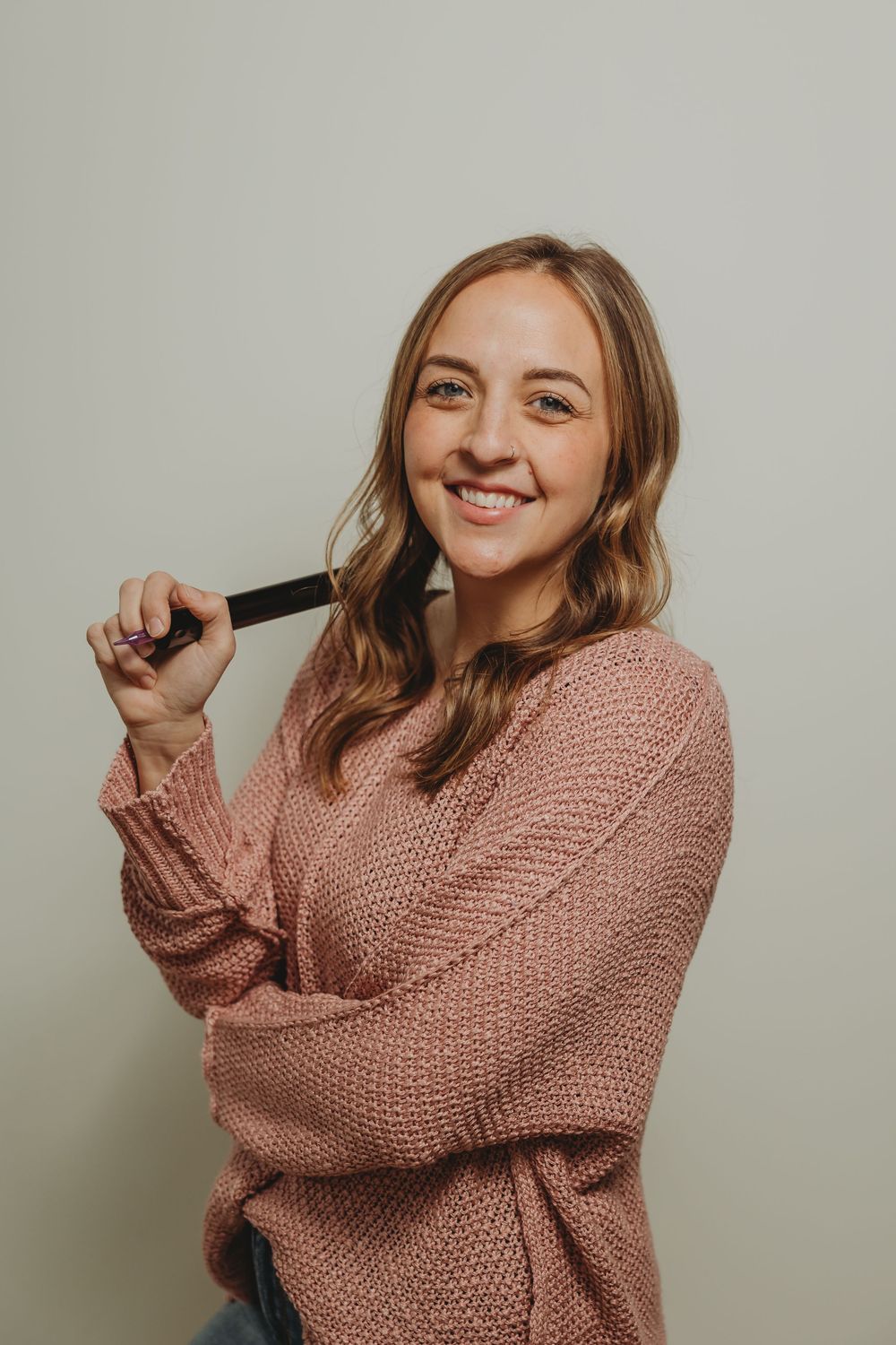 5 images of someone in a cozy pink knit sweater posing playfully against a beige wall.