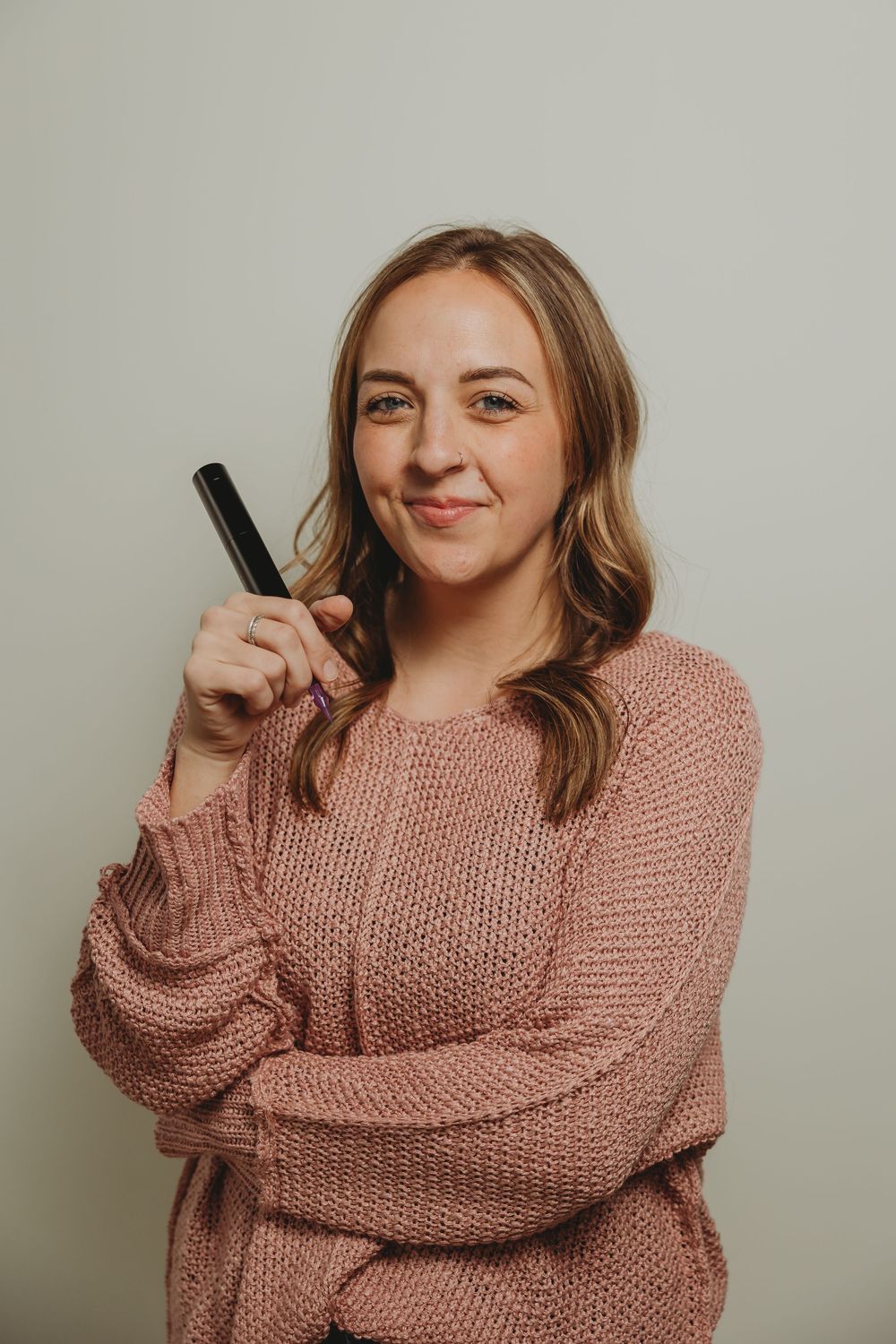 Woman in cozy pink knit sweater poses playfully in sequence showing different expressions and poses against neutral wall.