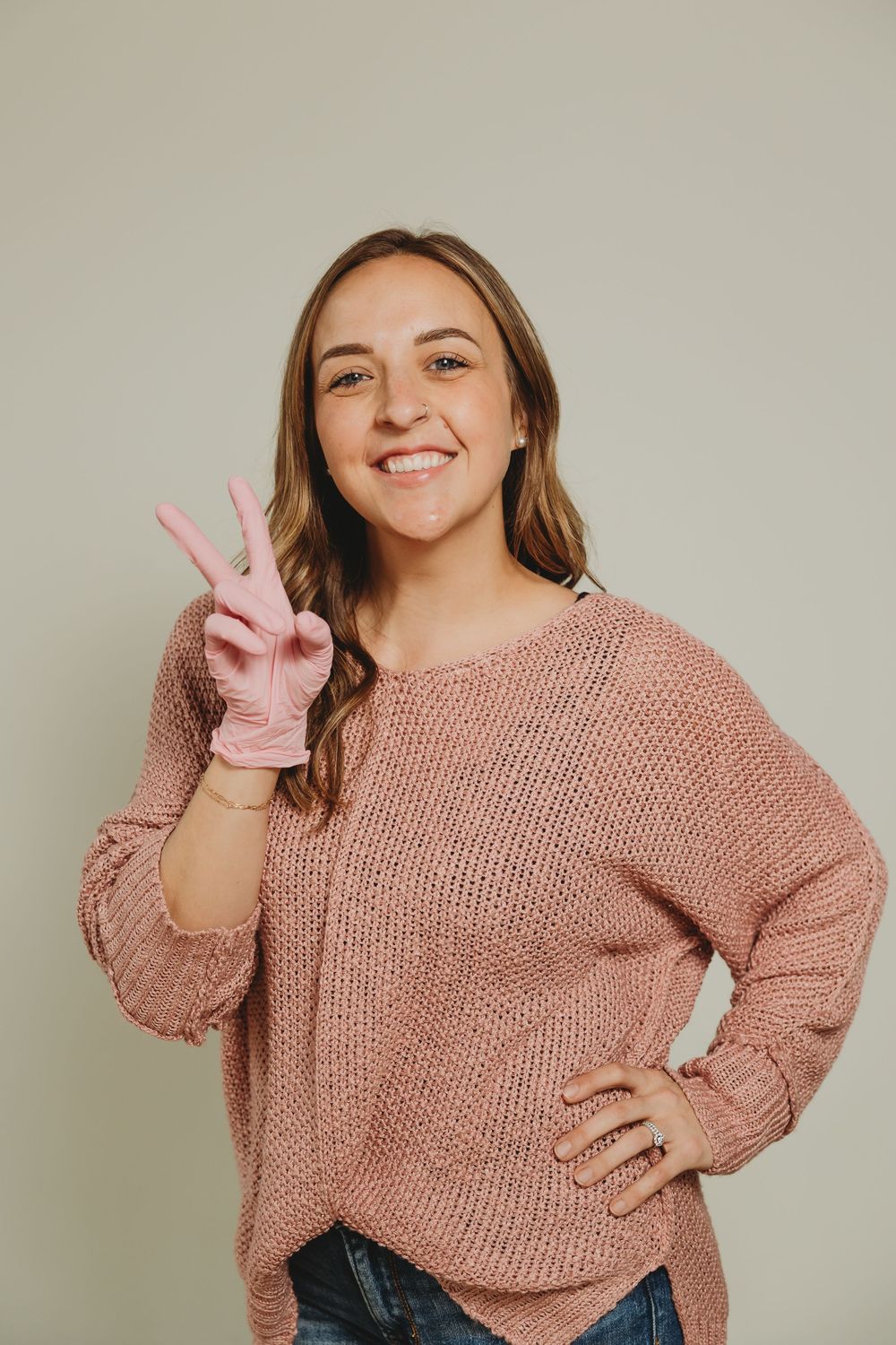 A person in a cozy pink knit sweater poses playfully against a neutral background.