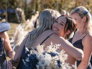 bride hugging bridesmaid with flower bouquet