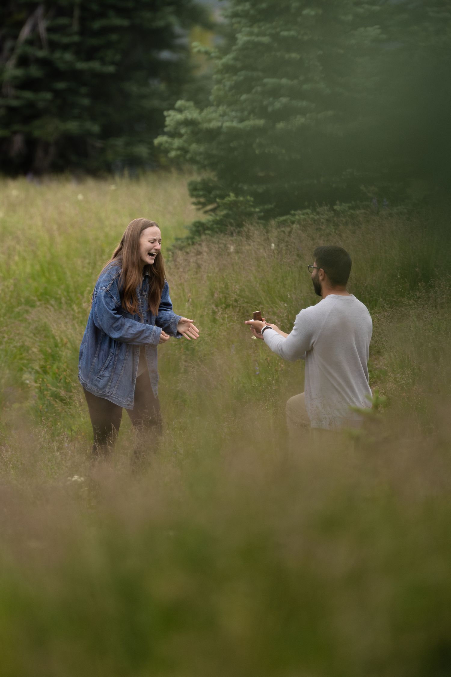 A man lifts his fiance in a lupine field during their engagement session in Puyallup.