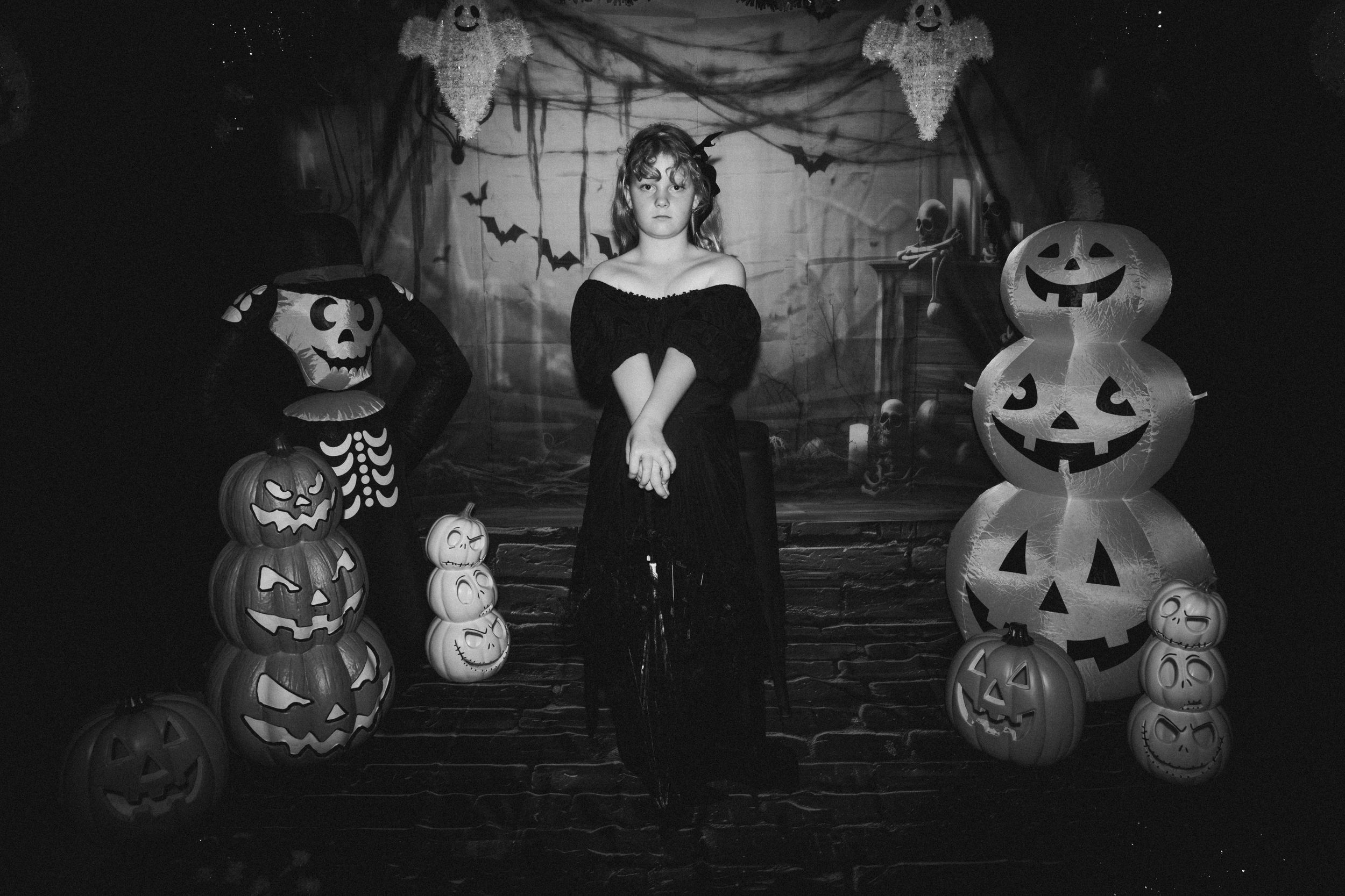 Vintage black and white Halloween scene with spooky decorations including glowing jack-o'-lanterns and cobweb backdrop.