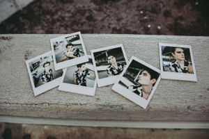 Several vintage polaroid photographs scattered on a weathered wooden surface in a nostalgic arrangement.
