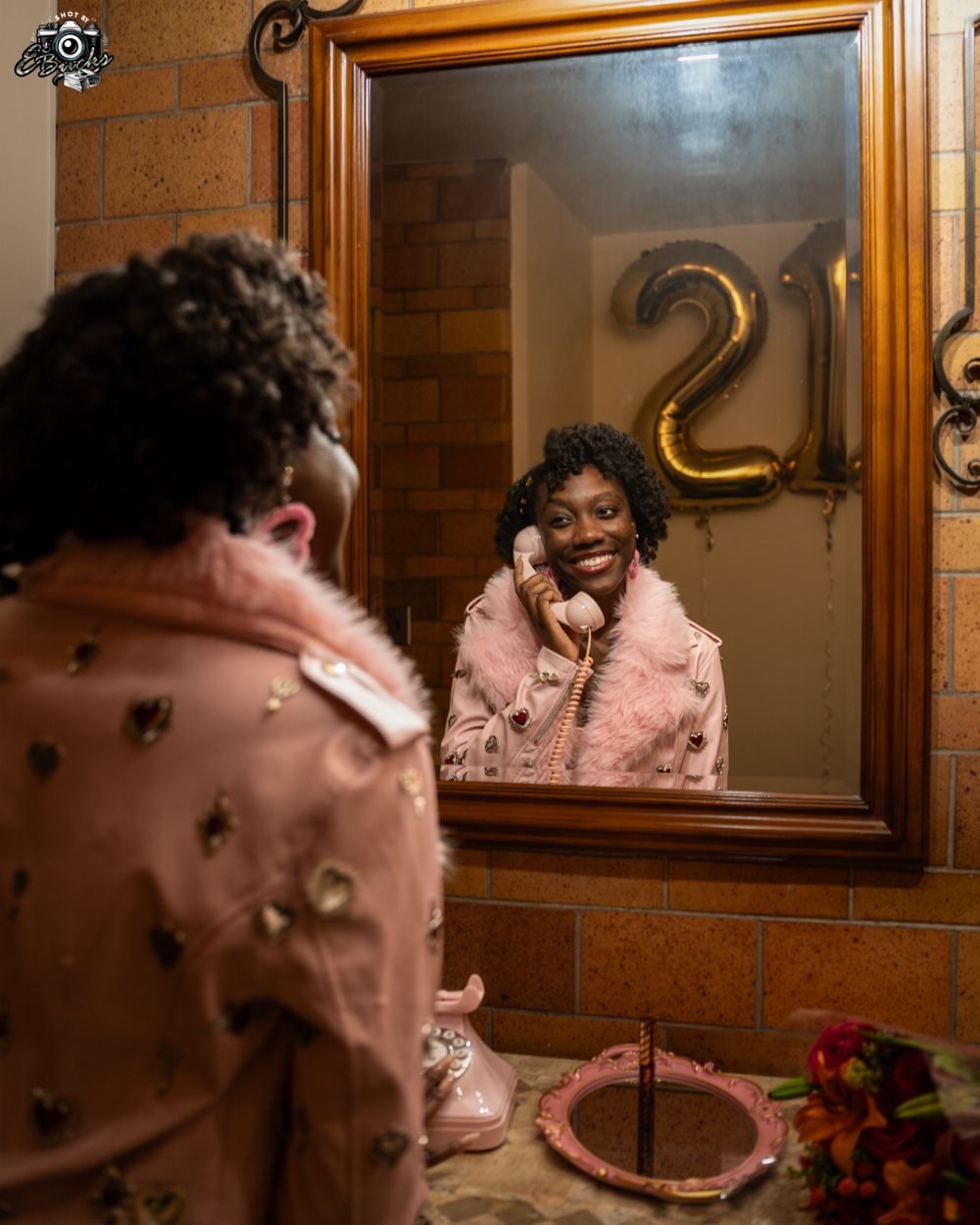 A mirror selfie moment with gold number decorations and flowers on the table.