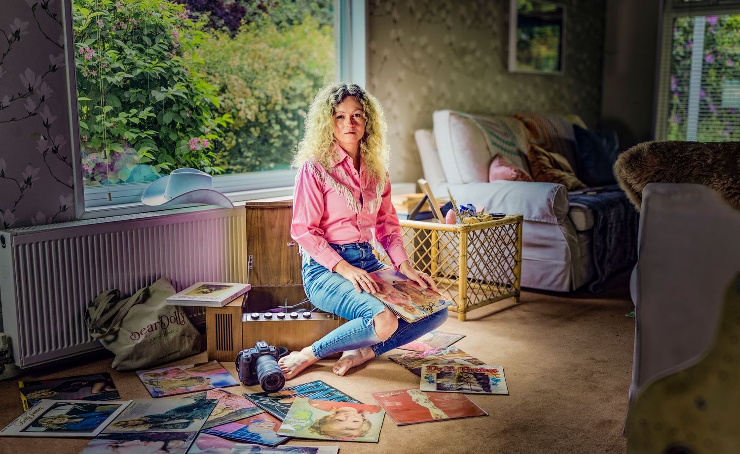 A casual lifestyle photo of someone sitting on the floor surrounded by vinyl records.