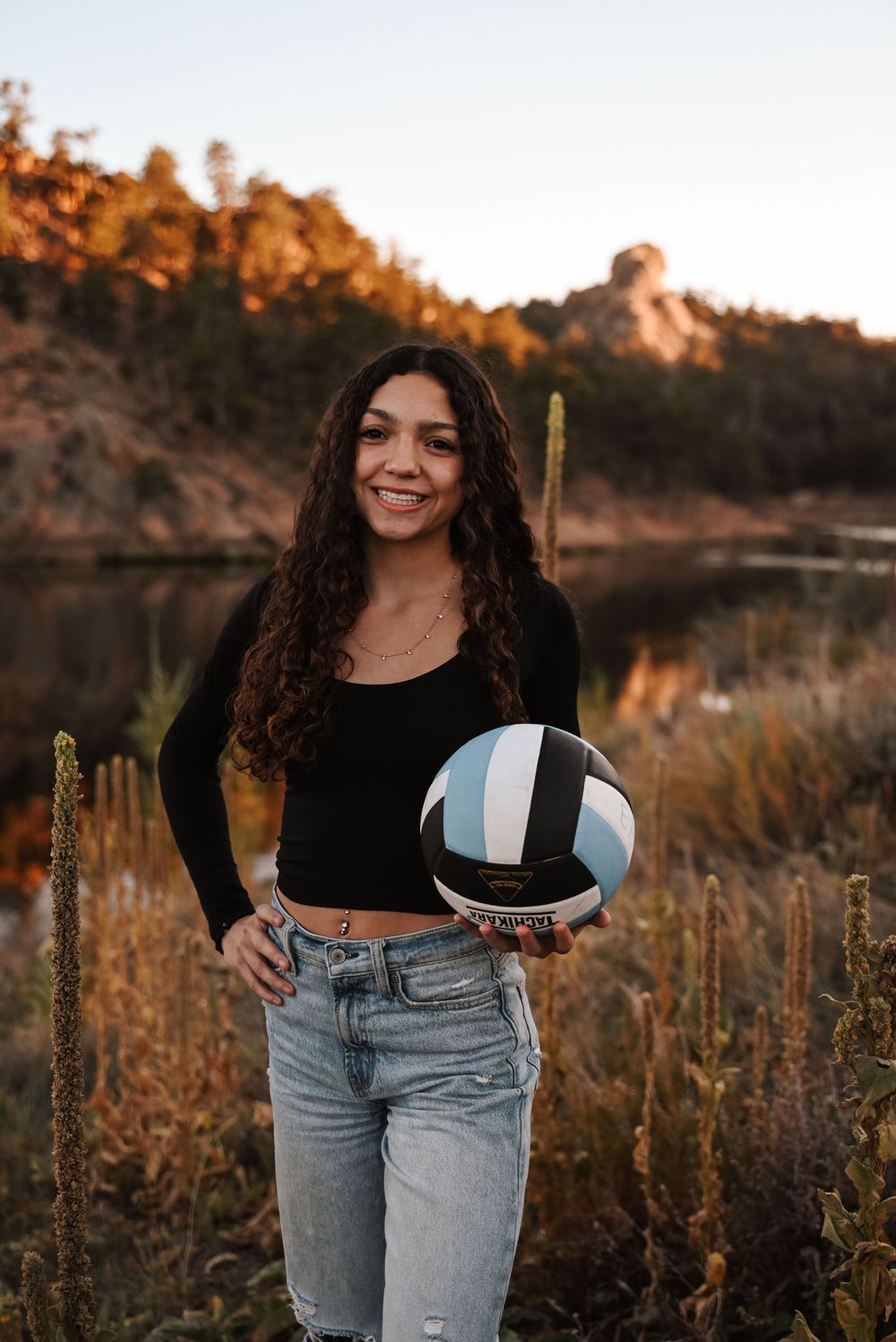 Casual outdoor portraits in jeans and black top against a natural landscape at sunset.