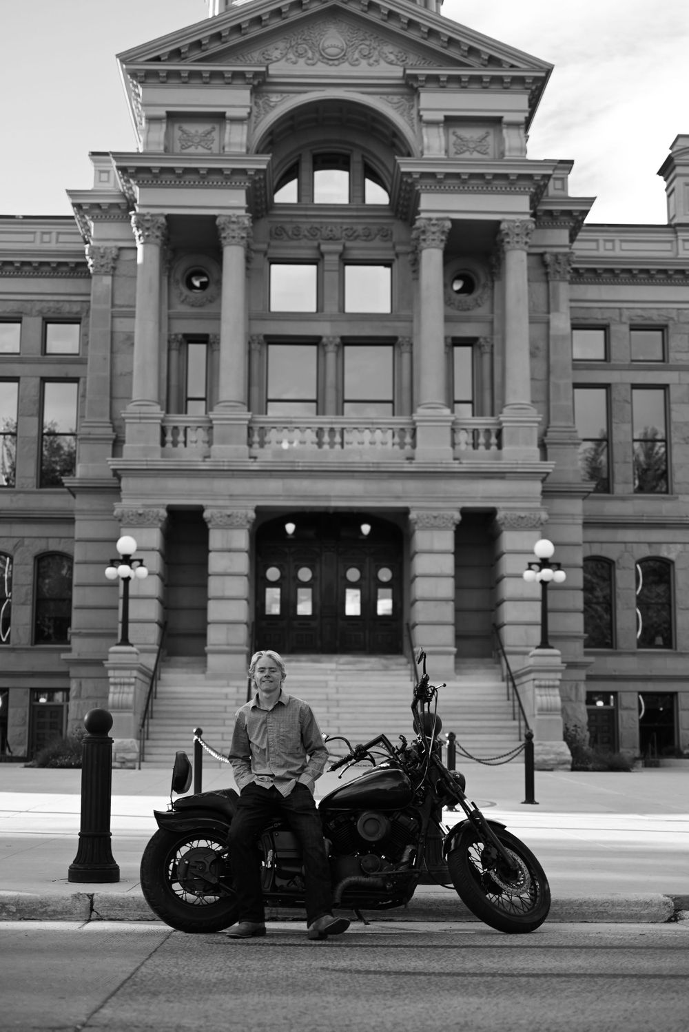 Black and white photo of motorcycle parked in front of grand historic government building.