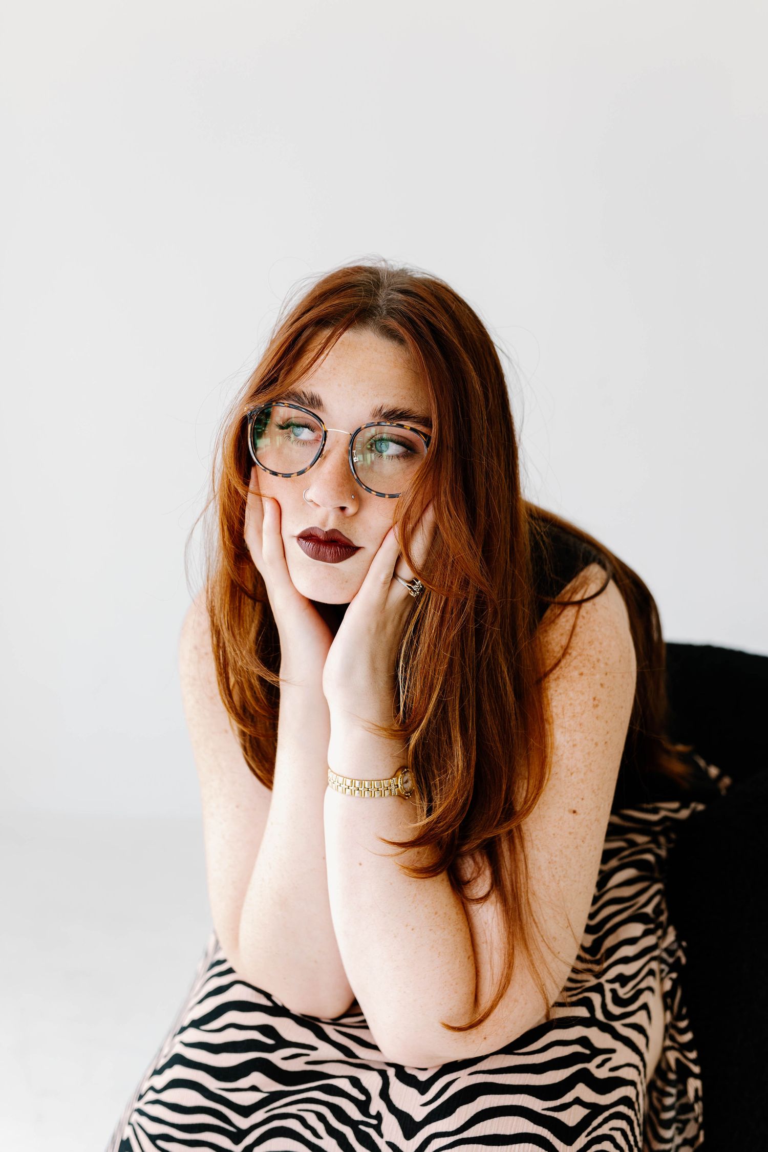 A person in glasses and a zebra print top poses playfully in a studio photoshoot sequence.
