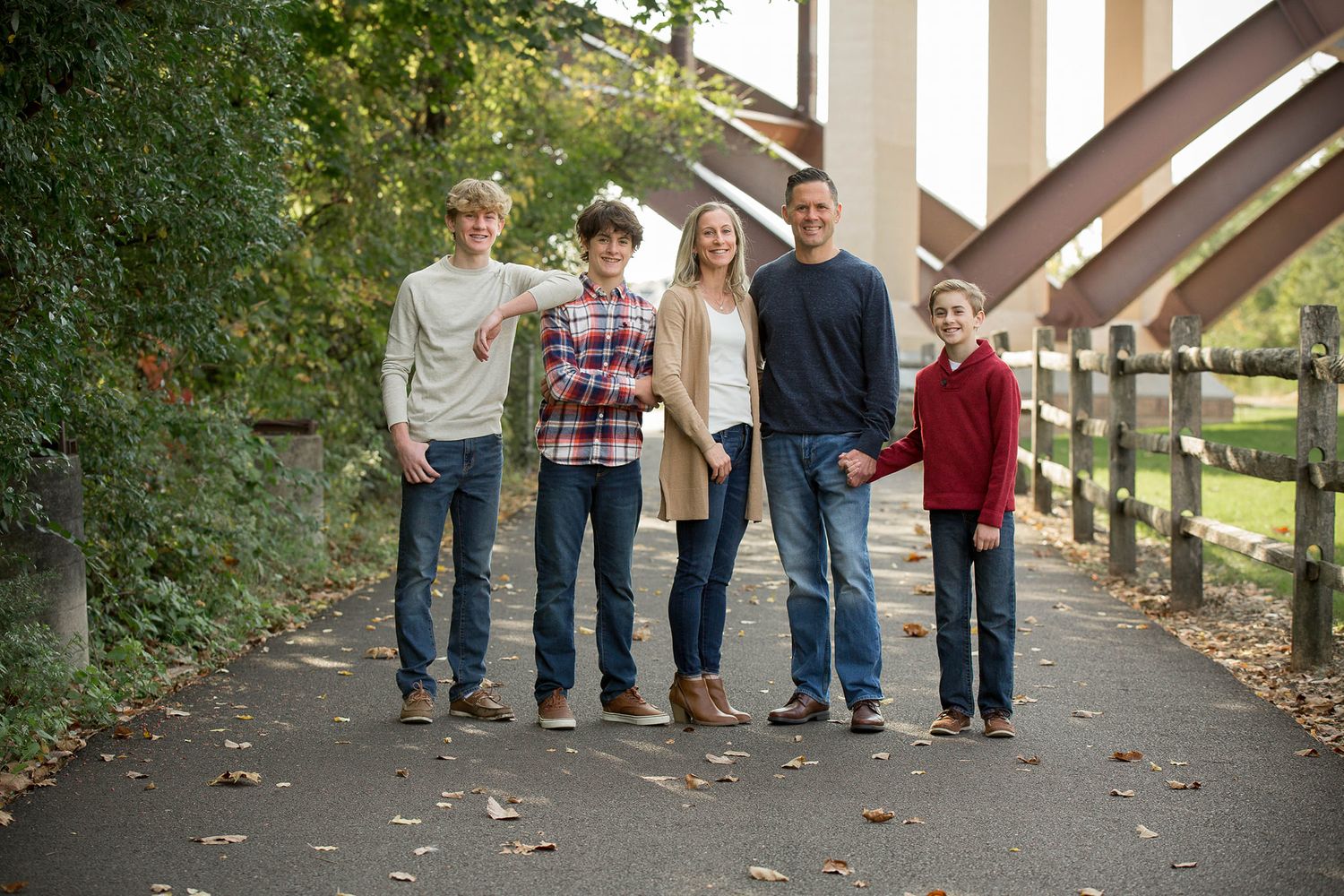 Family members' feet lined up on a pathway surrounded by fall foliage.