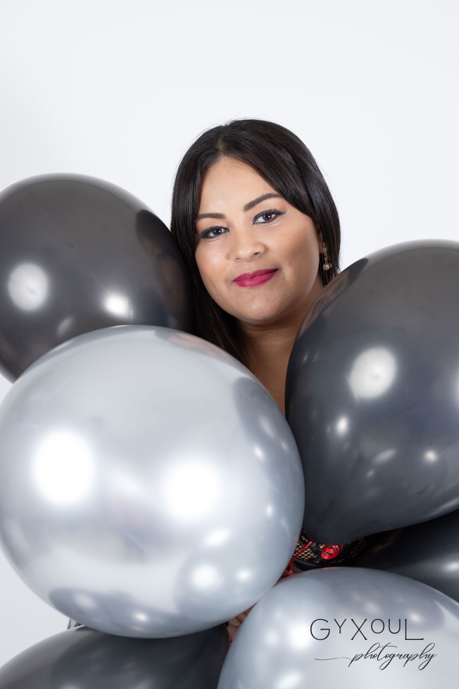 Modern portrait with silver and black balloons against white background.