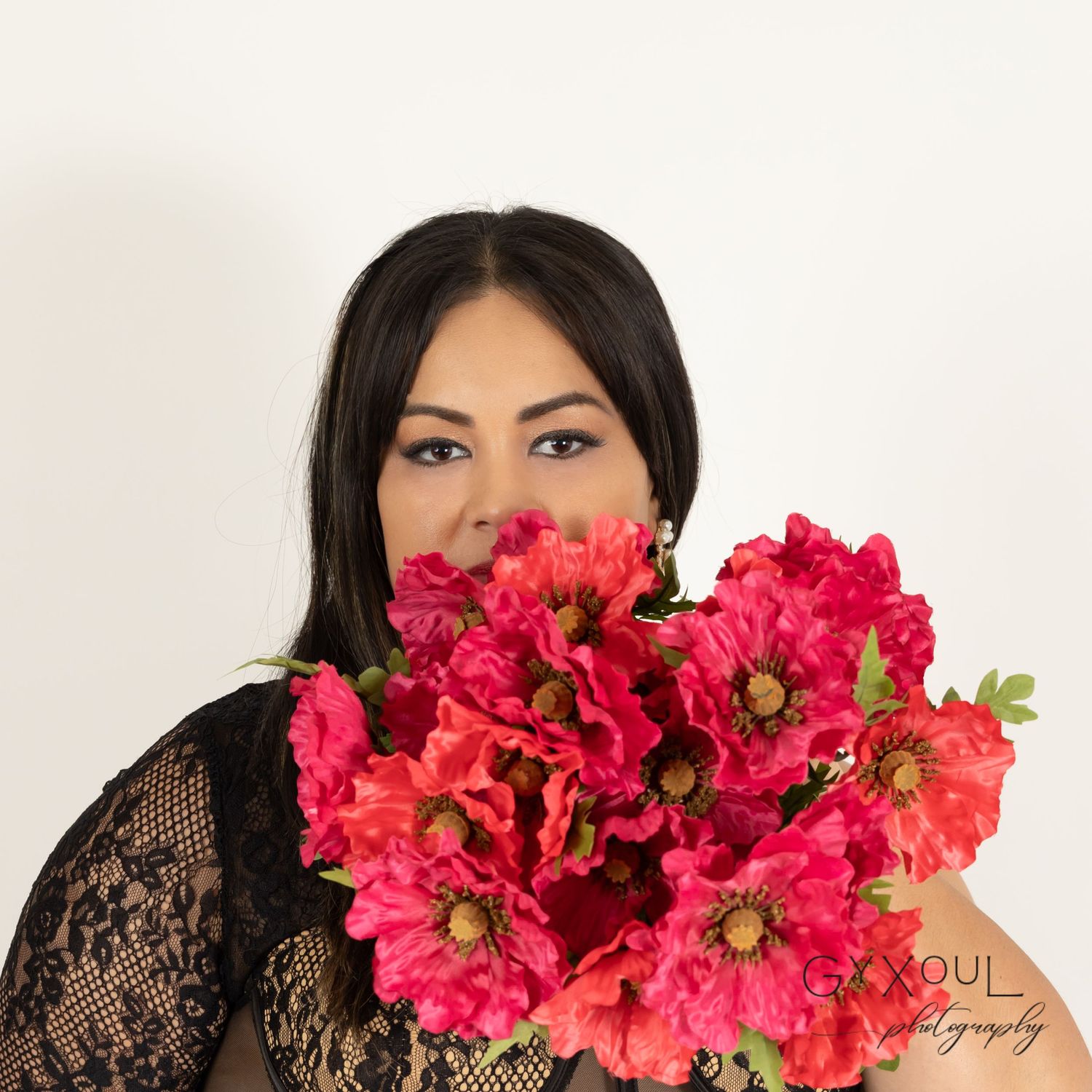 Glamorous portrait with vibrant red peonies and black lace dress.