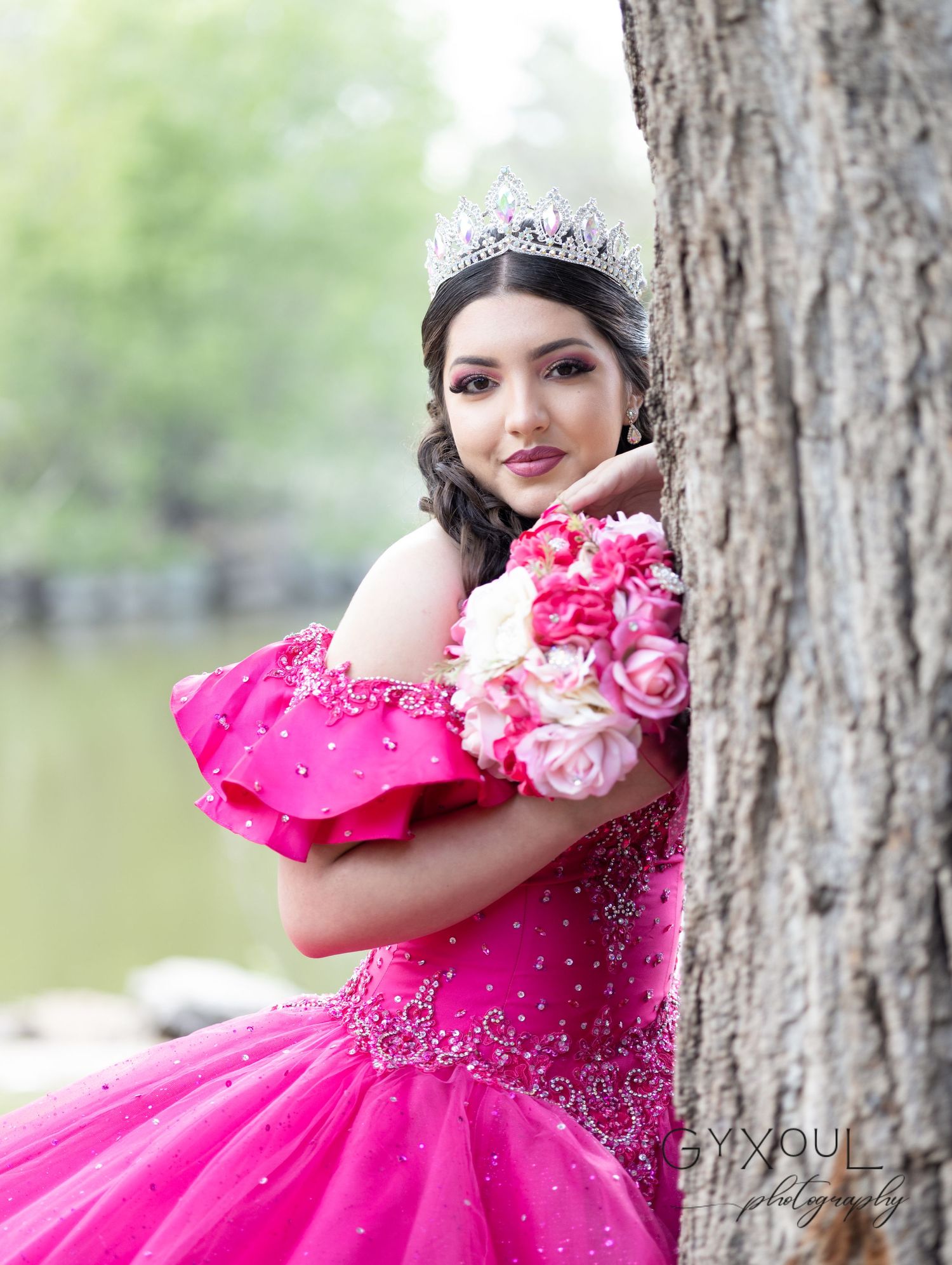 Bright pink ball gown with crystal details and floral bouquet in outdoor garden setting.