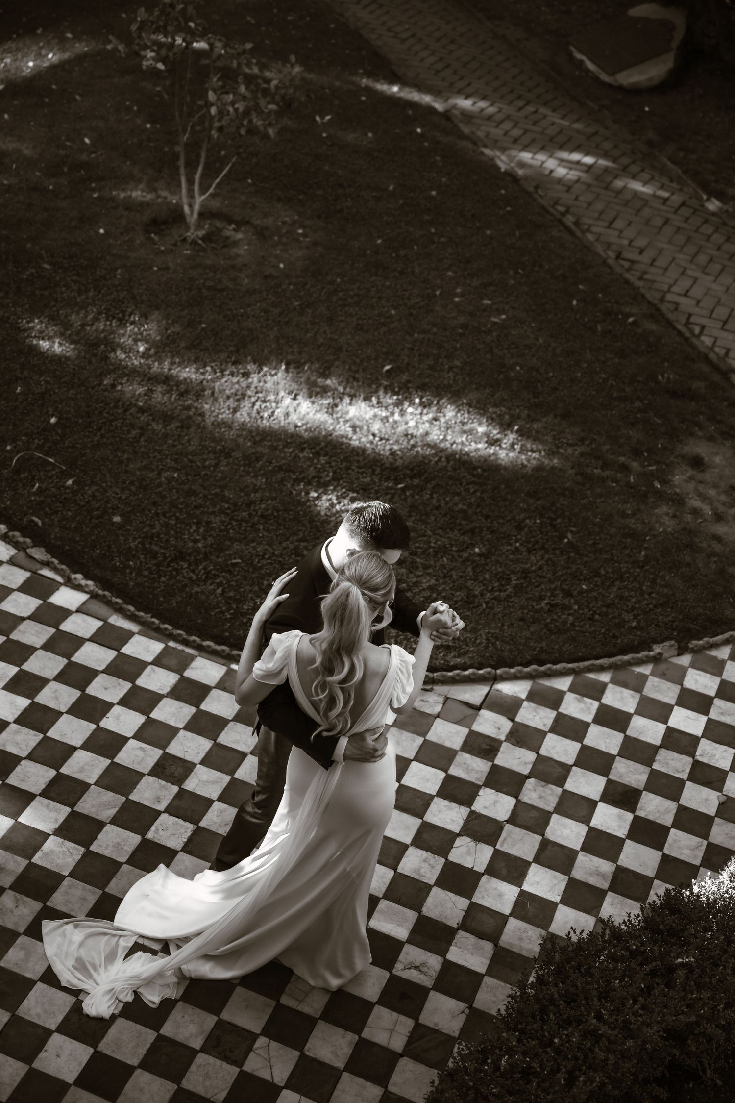 Bride twirling on checkered floor in elegant wedding dress.