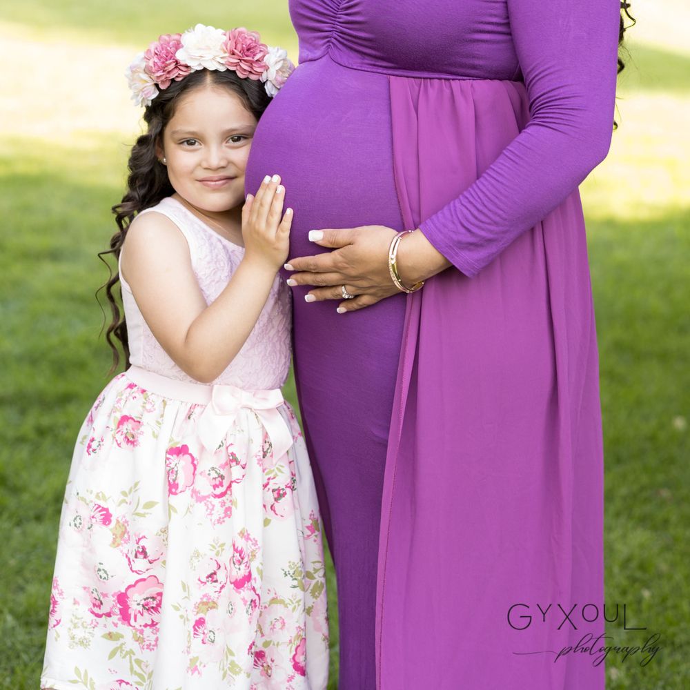 A maternity photo features contrasting purple and floral print dresses with flower crown details.