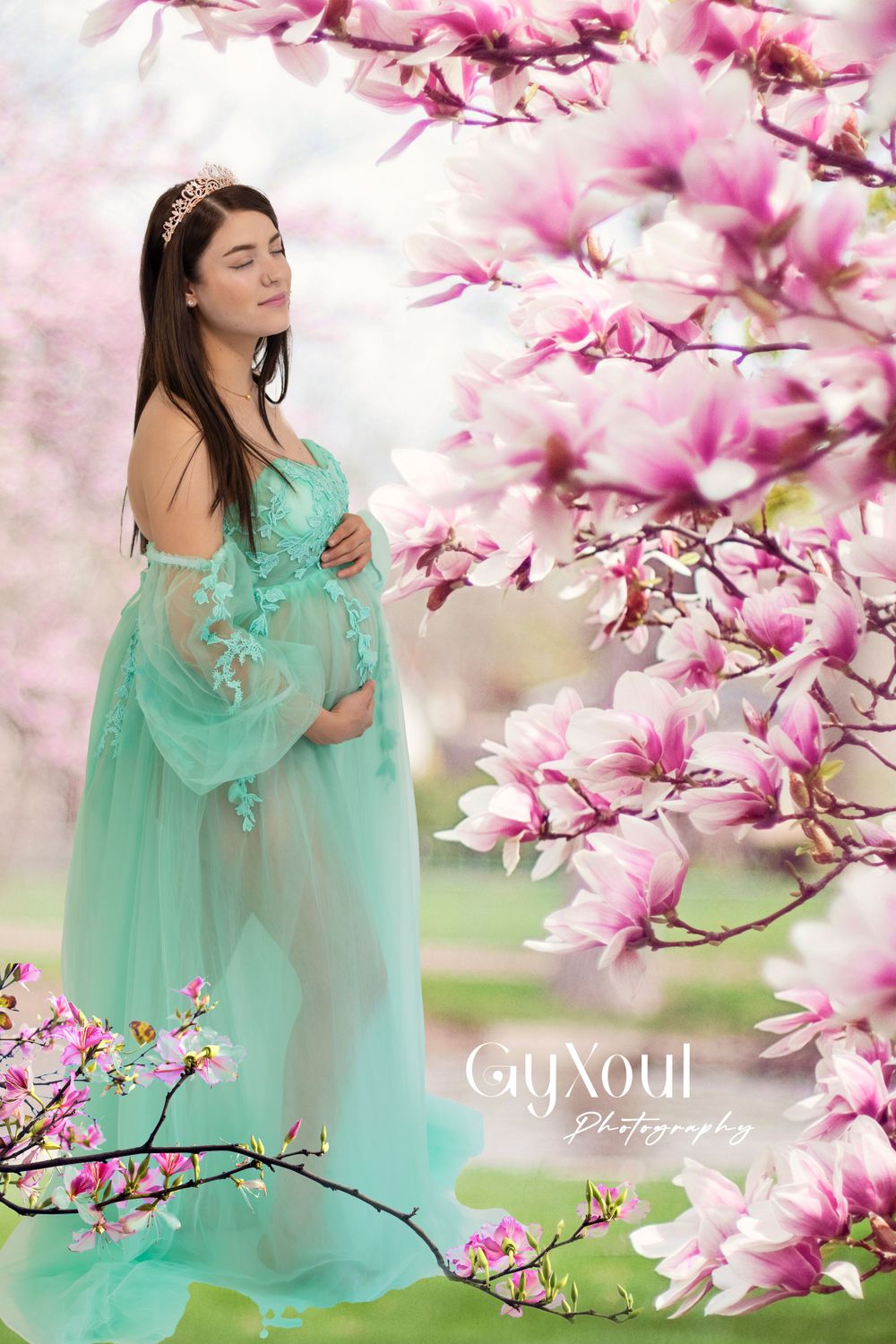 Dreamy springtime maternity portrait in turquoise gown among blooming magnolia branches.