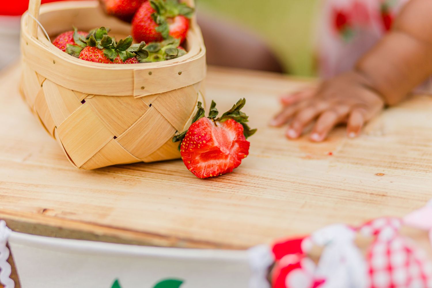 A close-up of fresh strawberries in a wooden basket on a table outdoors.