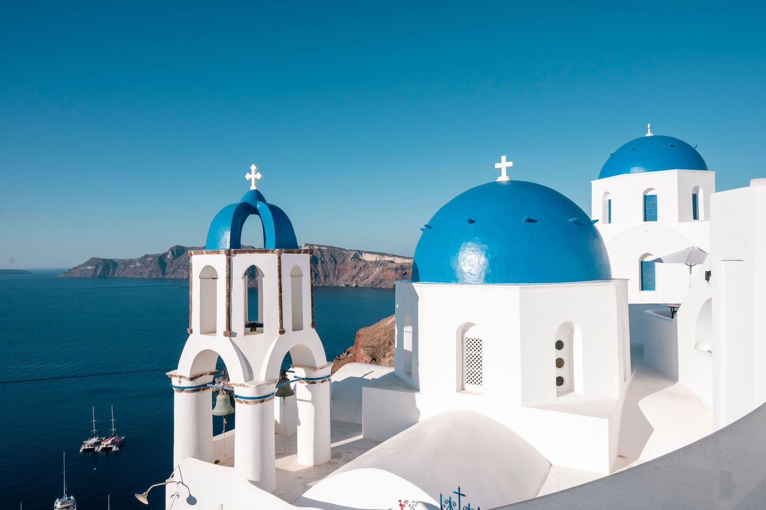 Iconic blue domed churches of Santorini against deep blue Mediterranean Sea and sky.