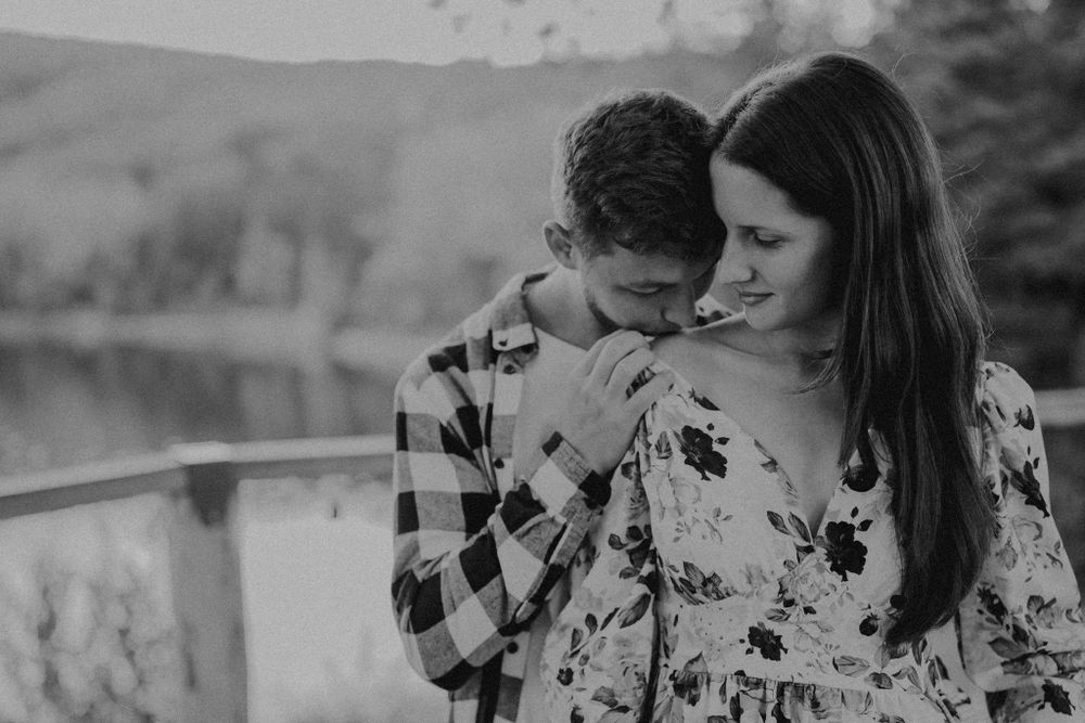 An intimate black and white portrait of a couple sharing a tender moment outdoors.