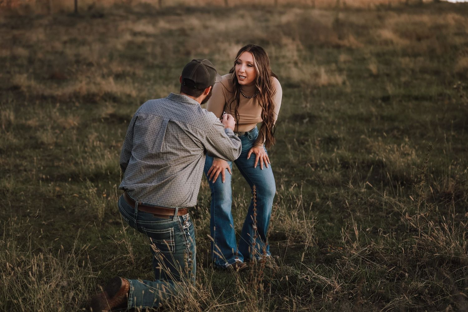 Couple sharing an intimate moment in a sunlit field during golden hour.