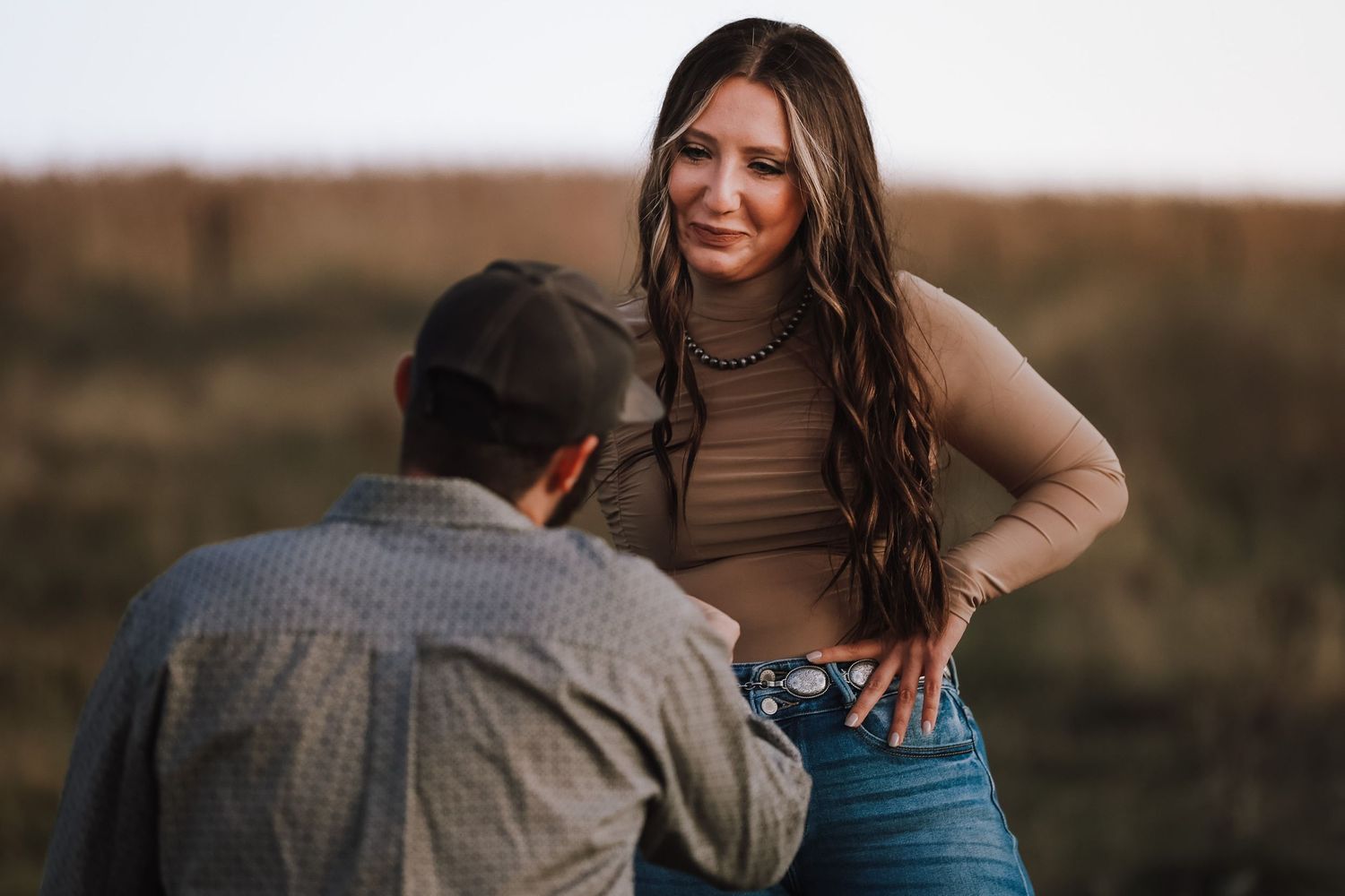 A proposal scene with casual-dressed individuals in a golden field.