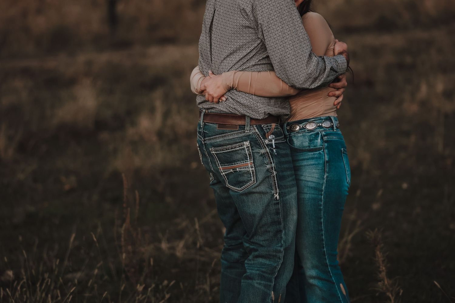 A couple embracing in casual denim against a dusky outdoor backdrop.