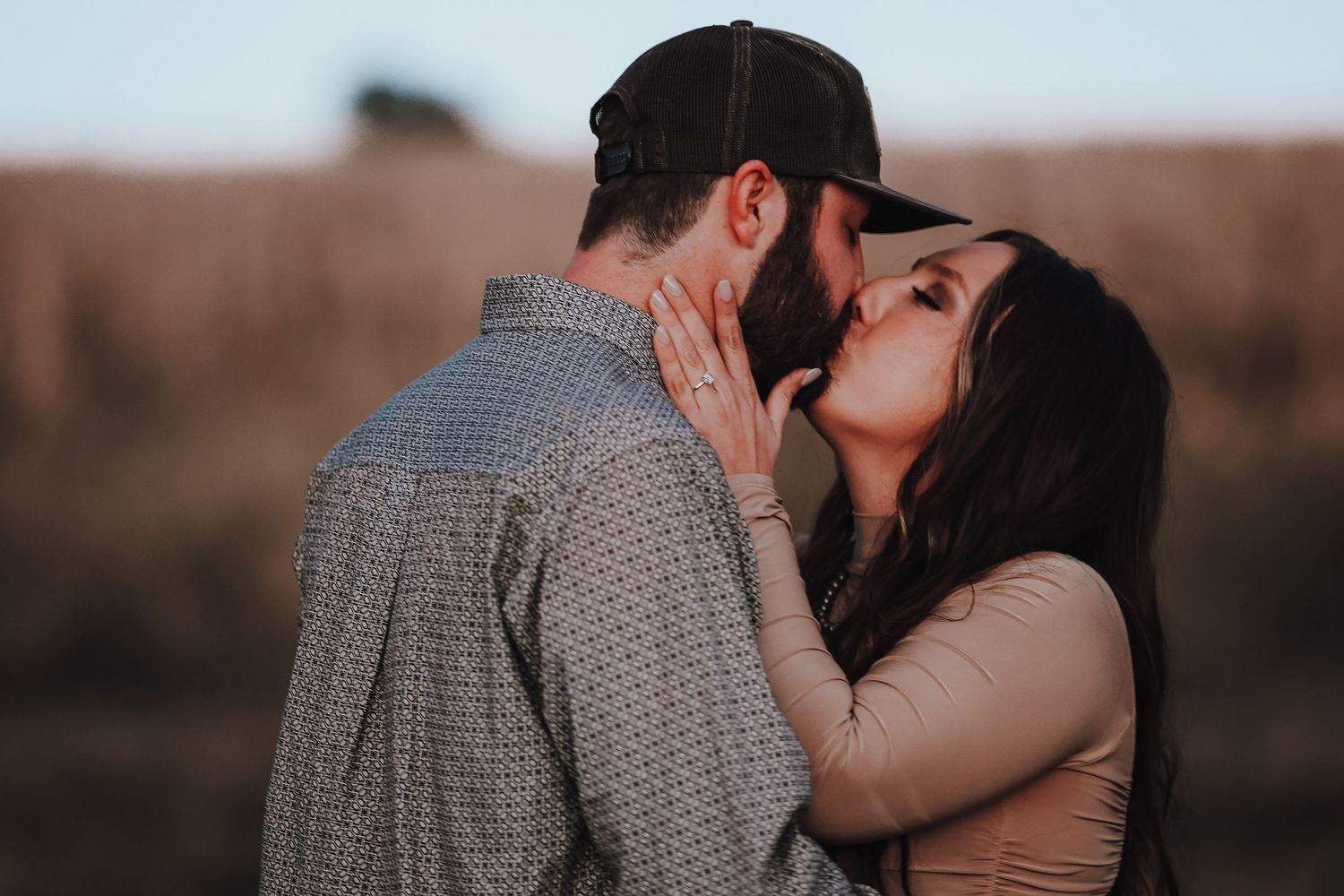 A romantic intimate moment between a couple during sunset in a field.