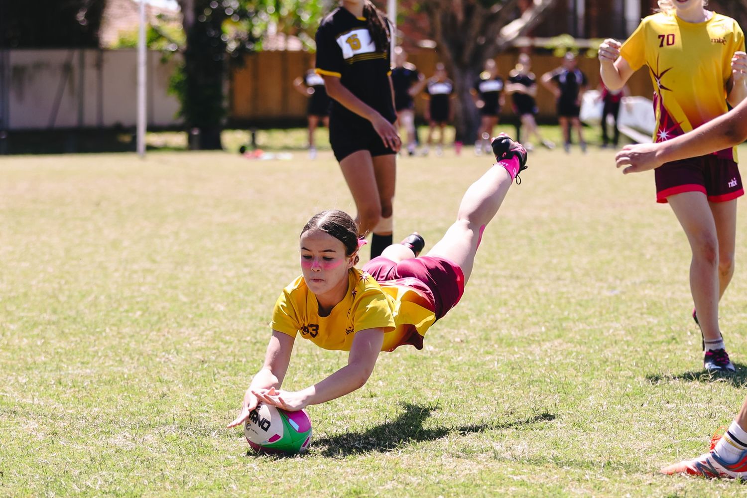 Rugby player diving to catch ball during match on grass field.