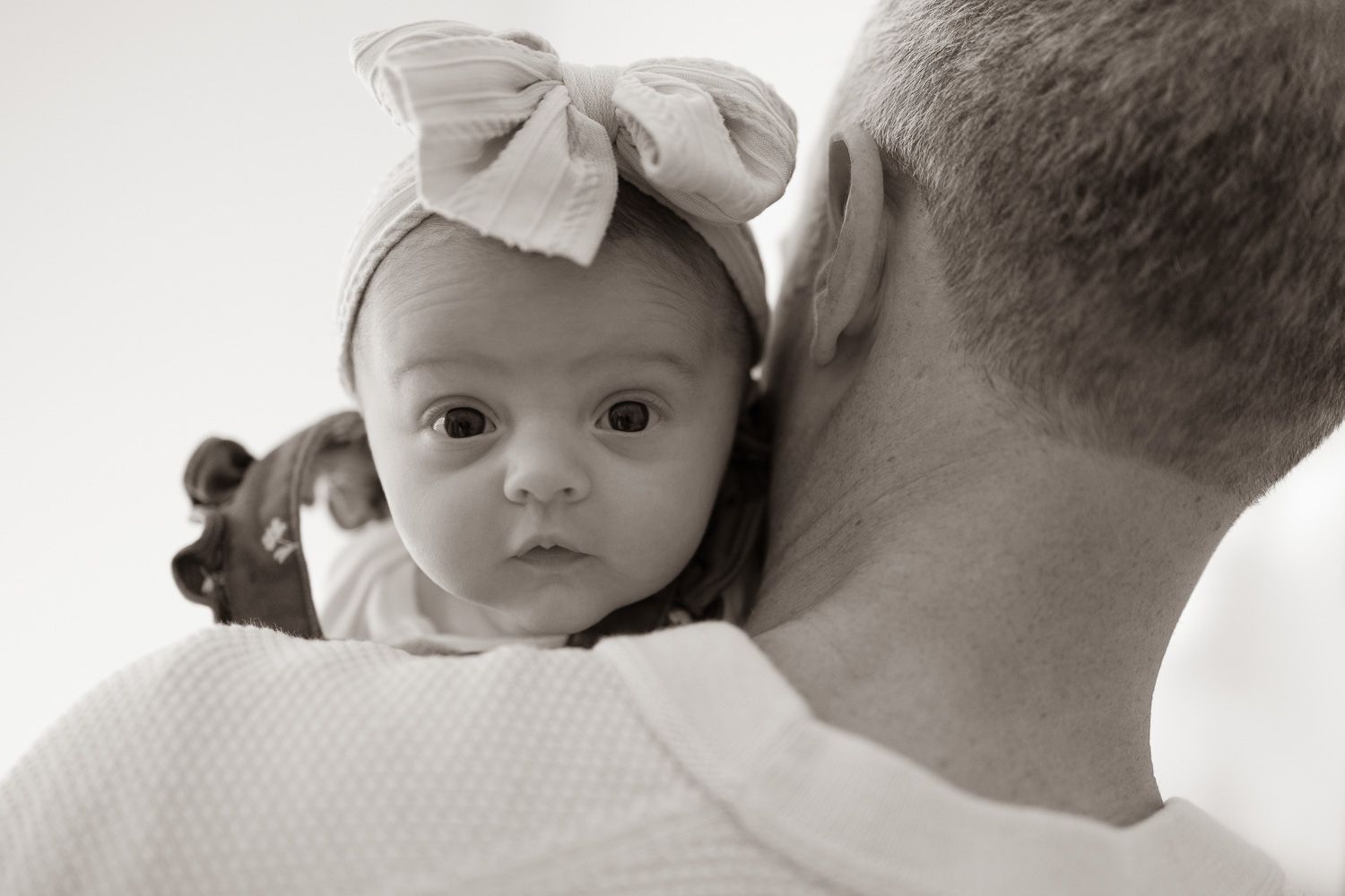 Baby peeks over shoulder at lifestyle in-home photo session by Bay Area Newborn Photographer Cindy Tucey in Los Gatos