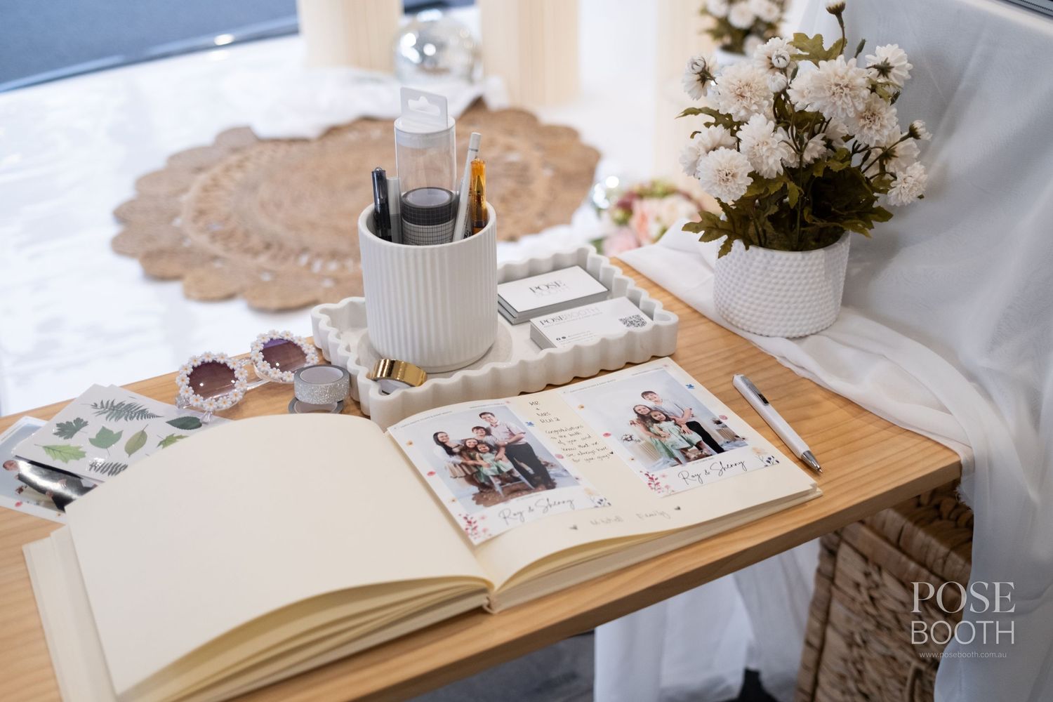 Open photo album with floral arrangements and decorative candles on a wooden table. Perth WA Photo booth Hire Event Booth
