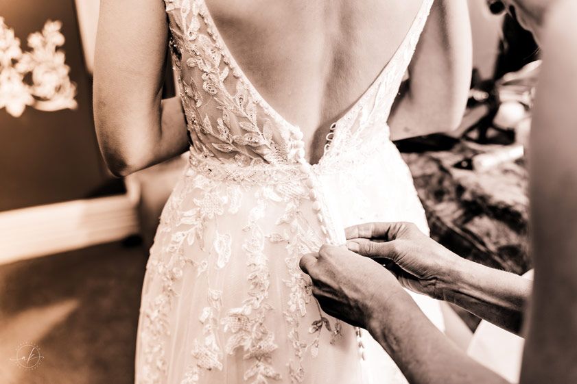 Details of intricate lace on a wedding dress being fastened.