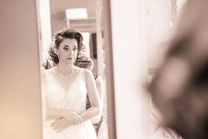 Soft focus wedding preparation scene with white dress and mirror reflection.