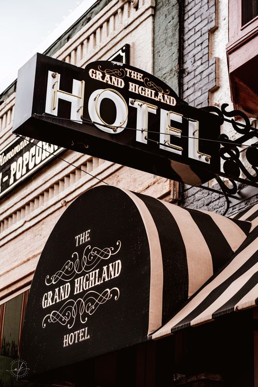 The Grand Highland Hotel's classic black and white striped awning and vintage signage on a brick building.