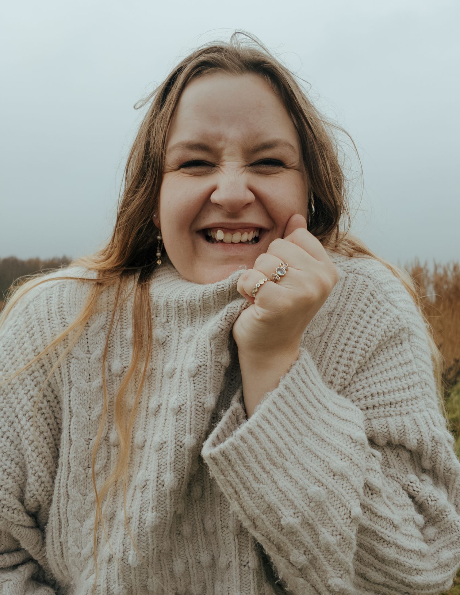 Person in cable knit sweater expressing joy with animated facial expression.