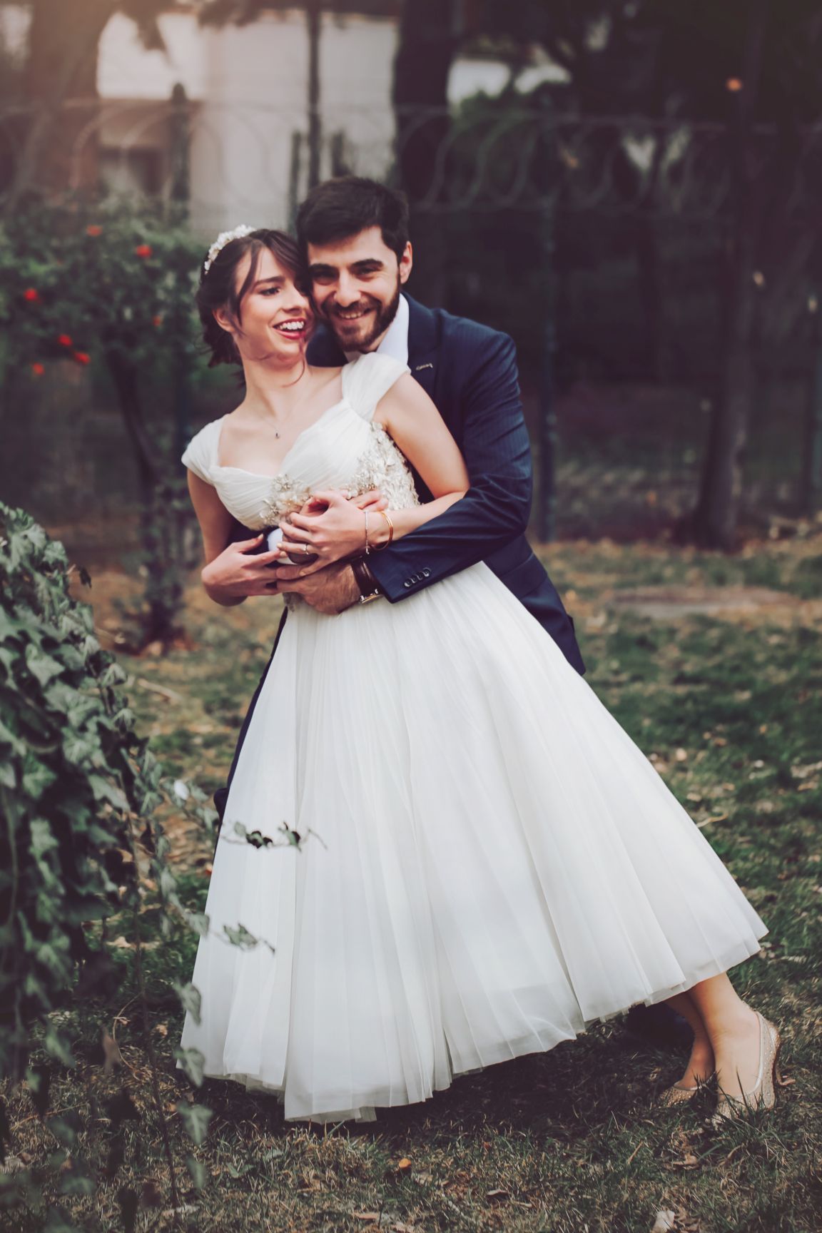 Romantic wedding portrait in garden with tea-length tulle dress.