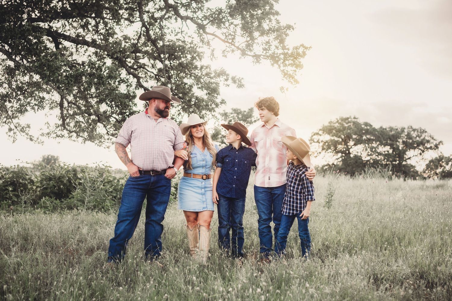 Family lifestyle portrait in a golden sunlit meadow with casual outfits.