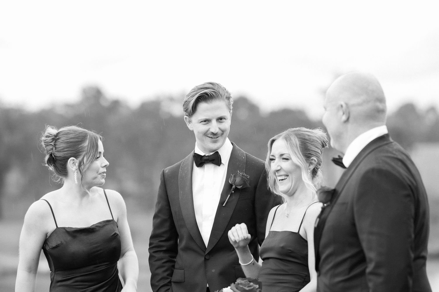Wedding party members share laughs during outdoor formal photos.