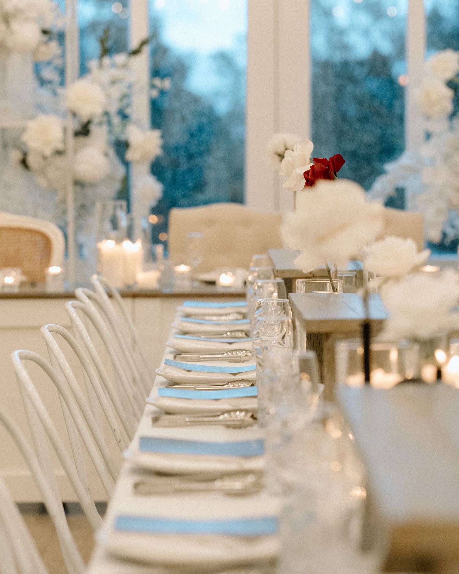 Elegant wedding reception table setting with white floral centerpieces and place settings.