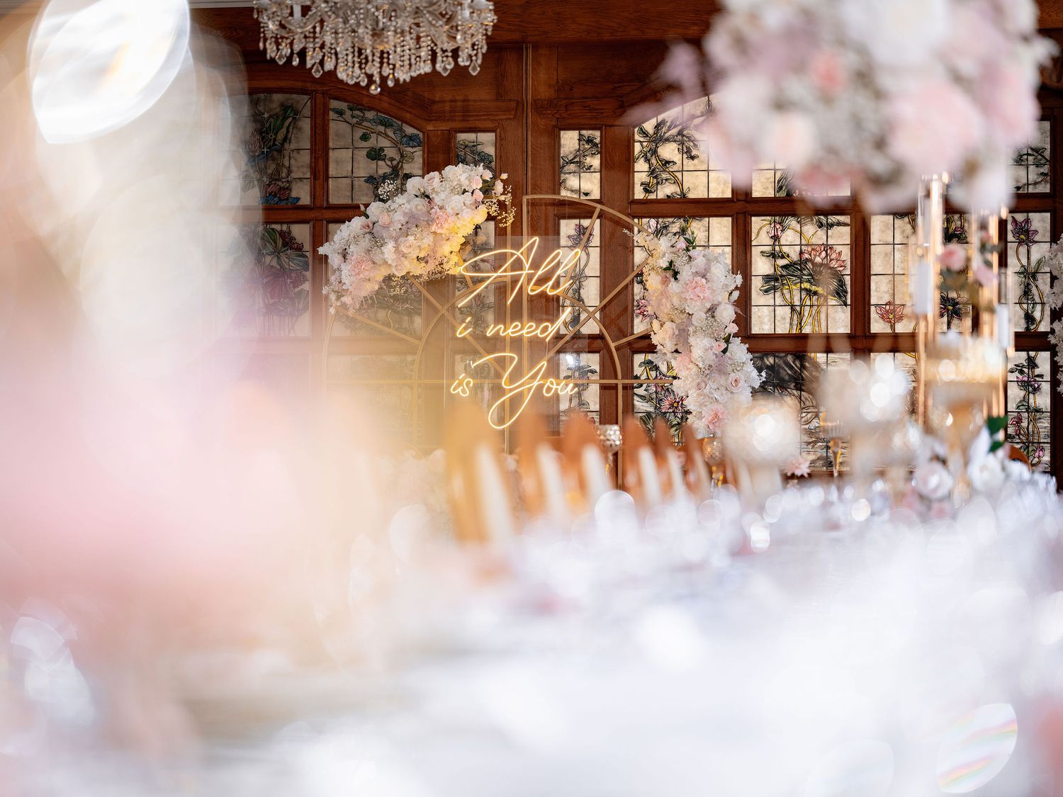 Dreamy bokeh view of a wedding reception venue with chandeliers and soft pink floral decorations.