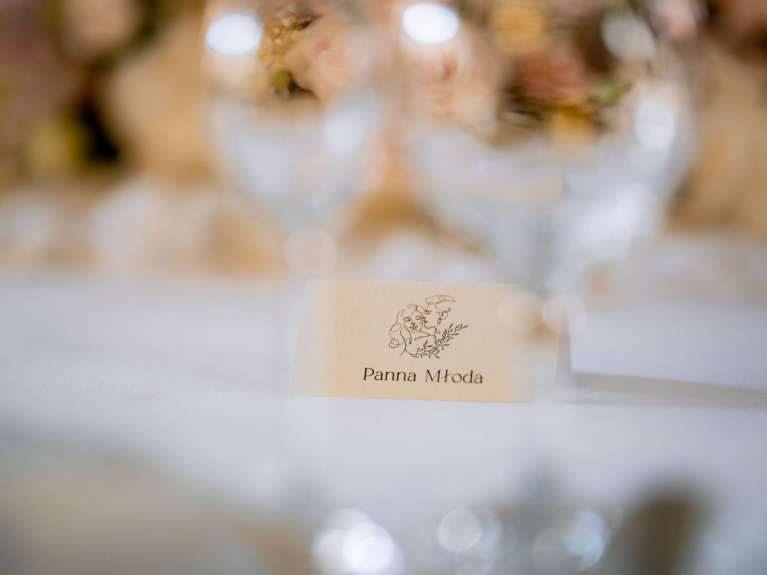 Close-up of a wedding place card with elegant calligraphy on a white tablecloth.