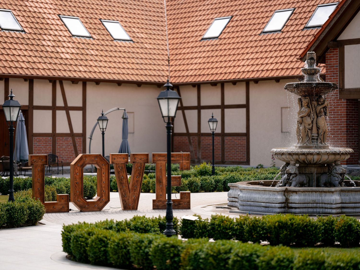 Courtyard garden featuring a traditional fountain and lamp posts against Tudor-style architecture.